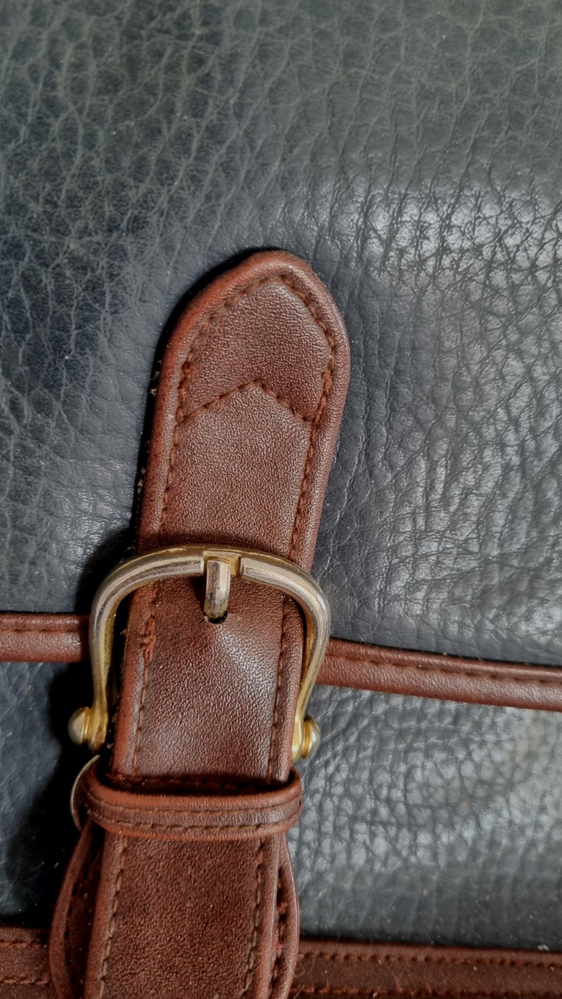 Cartera cuero negra y marrón con hebilla.